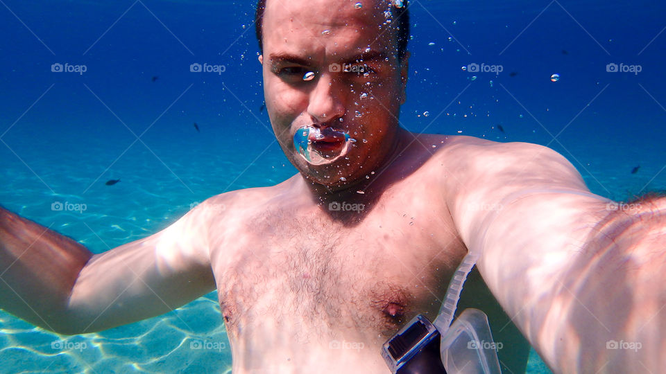 Young shirtless man swimming underwater