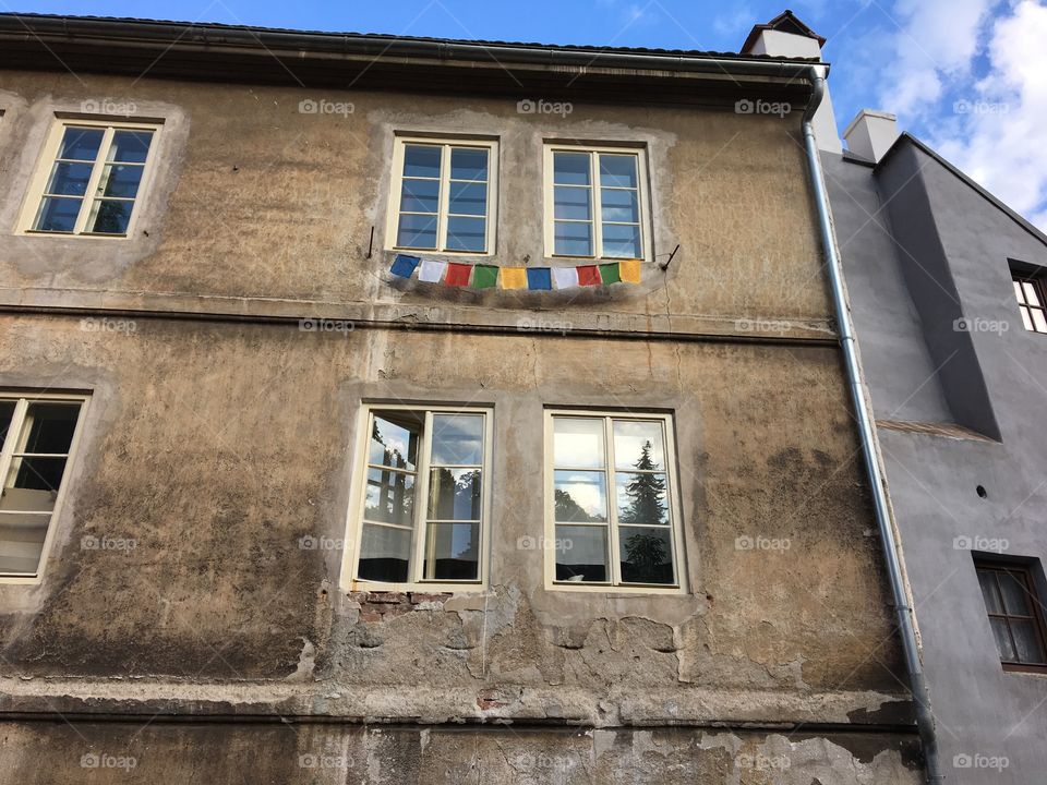 Colourful bunting hanging outside under an upstairs window 