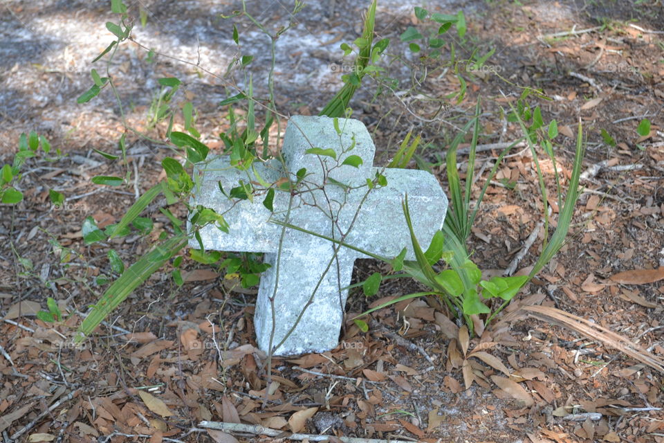 Small concrete cross on ground in cemetery