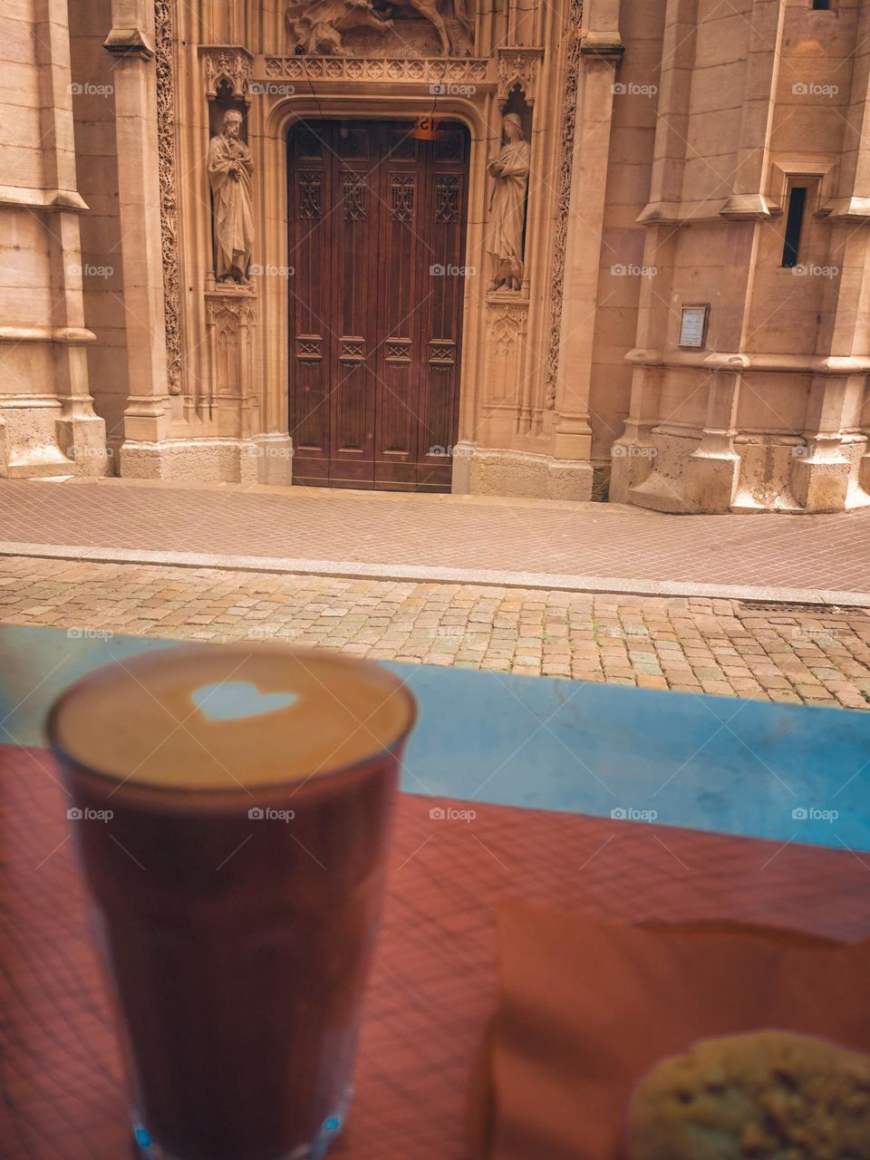 Cappuccino with heart in front of a church