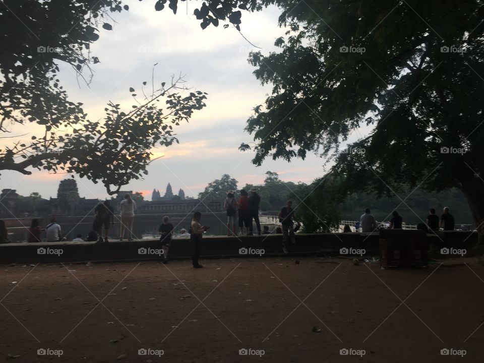 Sunrise at Angkor Waat, Cambodian Ruins of a Hindu Temple from The 12th Century with tourists standing by. 