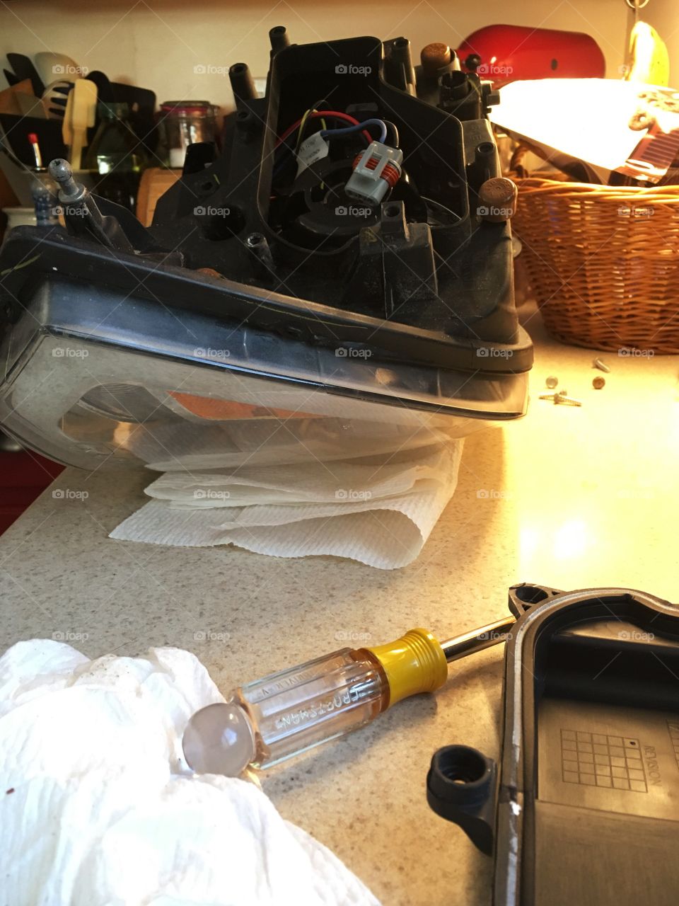 Car repairs occurring on the kitchen counter - replacing a headlight lamp is not an easy job