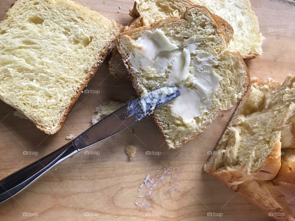 Spreading butter on brioche slice 