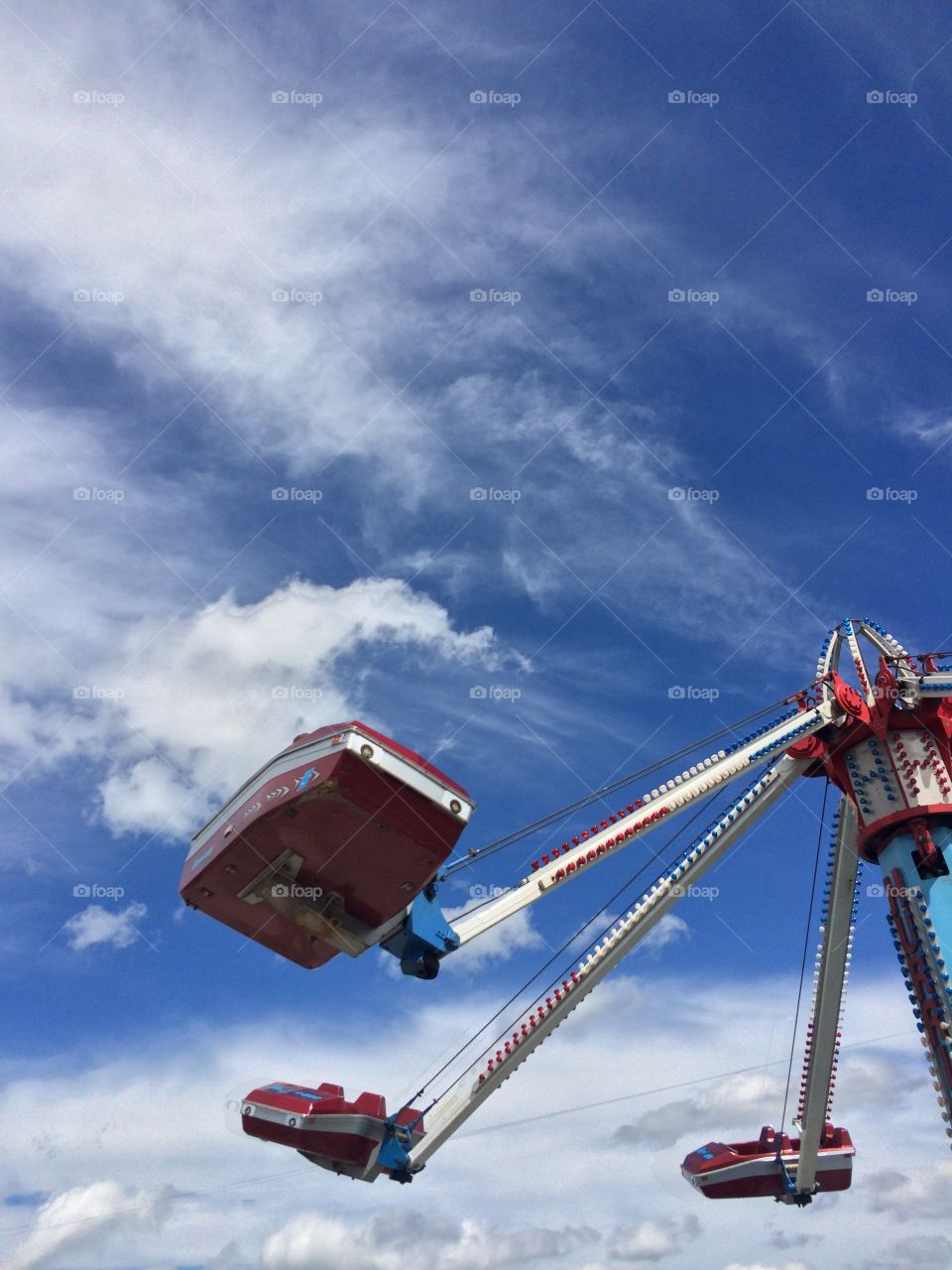 Carnival ride in motion with a bright blue sky and white fluffy clouds