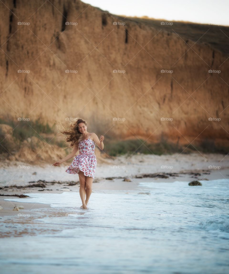 Portrait of beautiful young woman near the sea at sunset