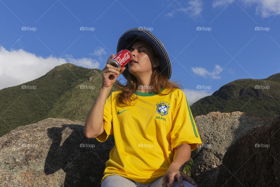Woman drinking Coca Cola on the mountain.