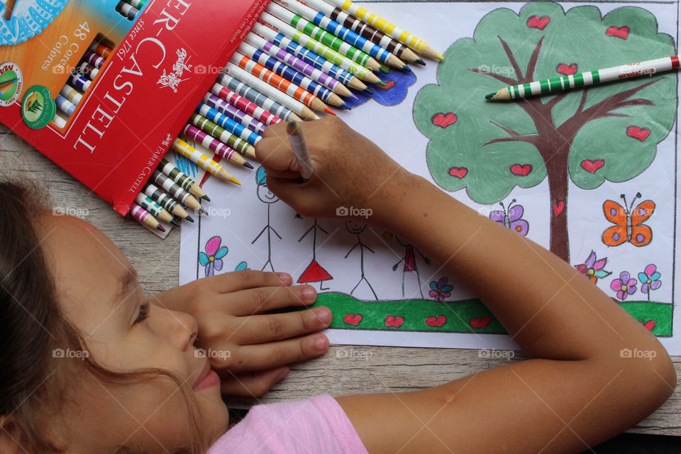 Girl coloring drawing with lapis Faber Castell