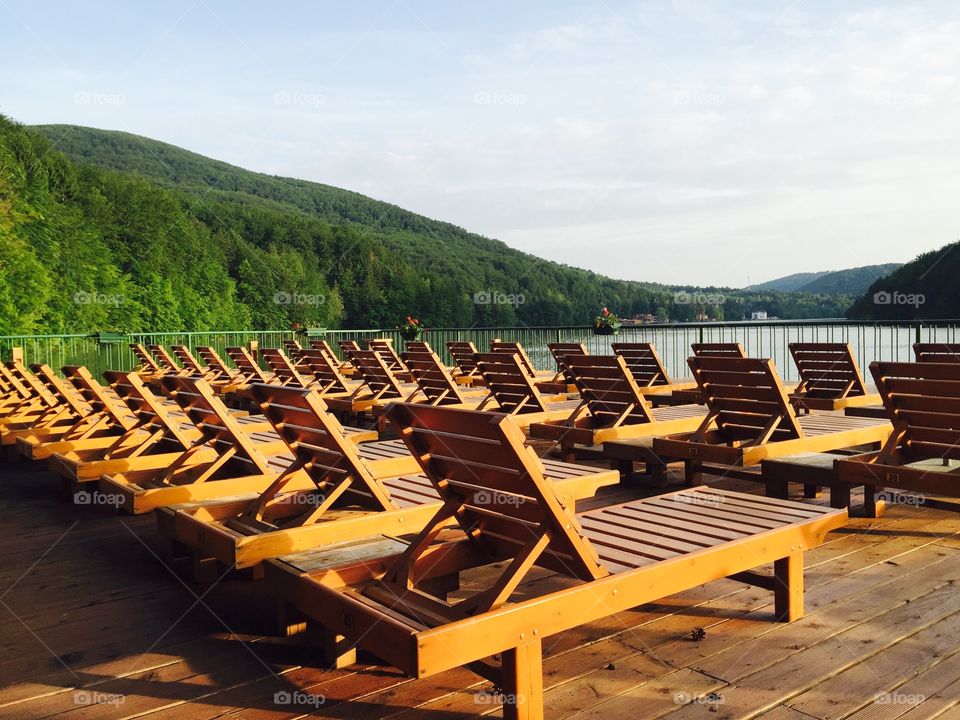 Beach with empty wooden sunbeds near the lake