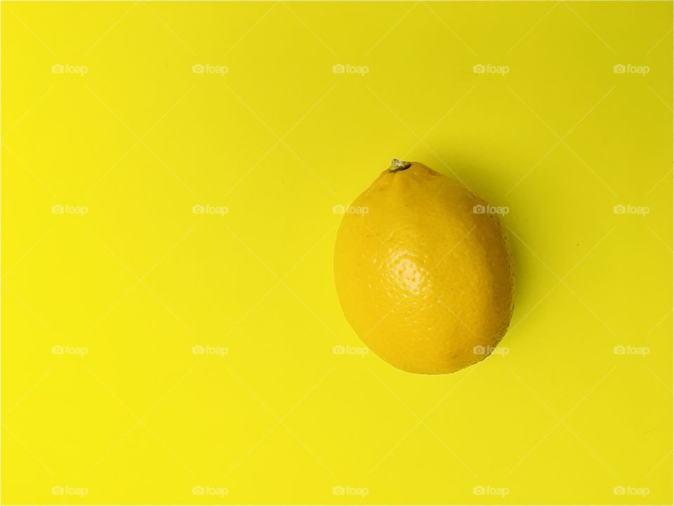 Yellow lemon on yellow background