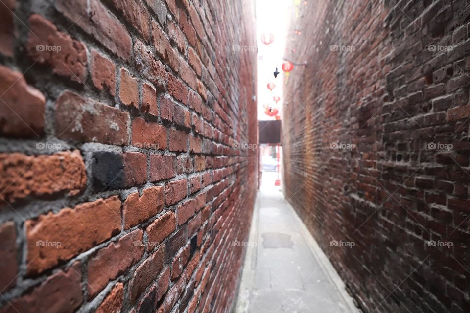 Brick walls surrounding a narrow alley 