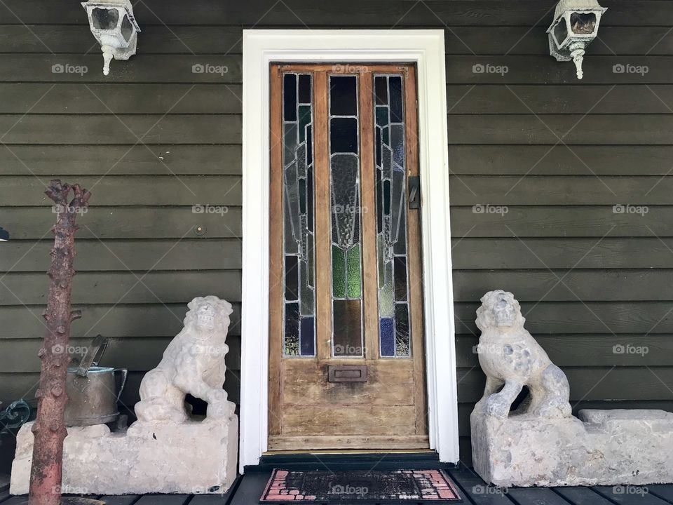 Wooden front door on a house with lion statues on both sides