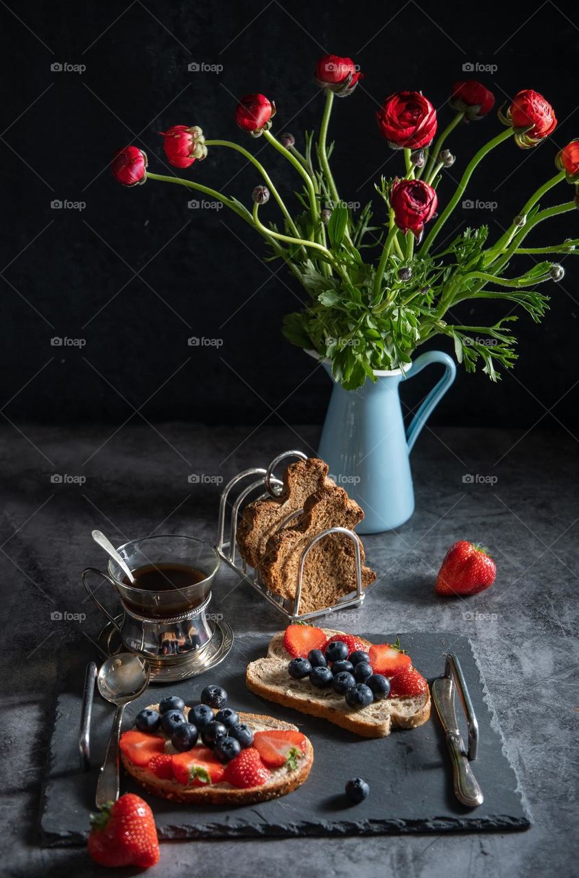 spring still life with red ronunculi and sweet sandwiches with strawberries and blueberries on bread in the form of rabbits, Easter theme,