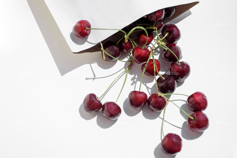 Cherry berries are scattered over a white background. Top view, flat lay