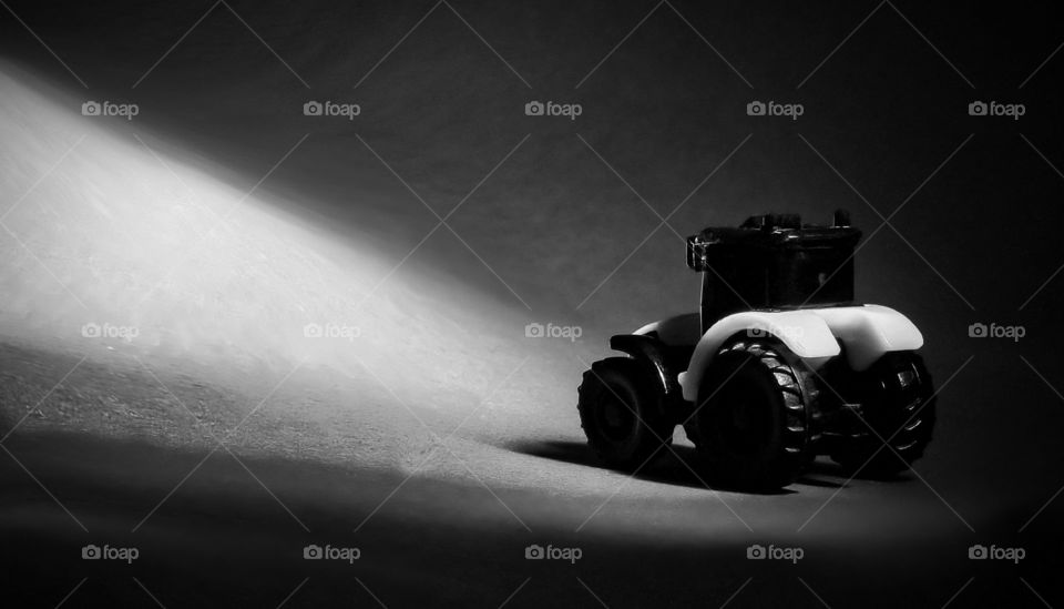 Toy agricultural machinery tractor black and green on a dark background.