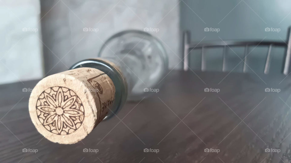 A glass bottle with a cork stopper placed on a brown table.