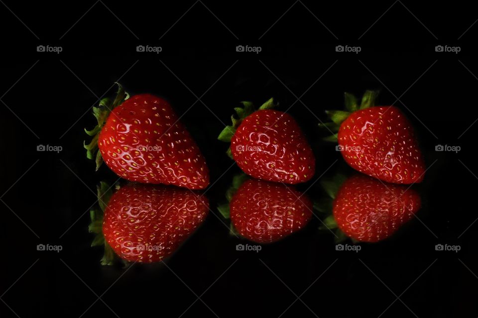 Three red strawberries on black background 