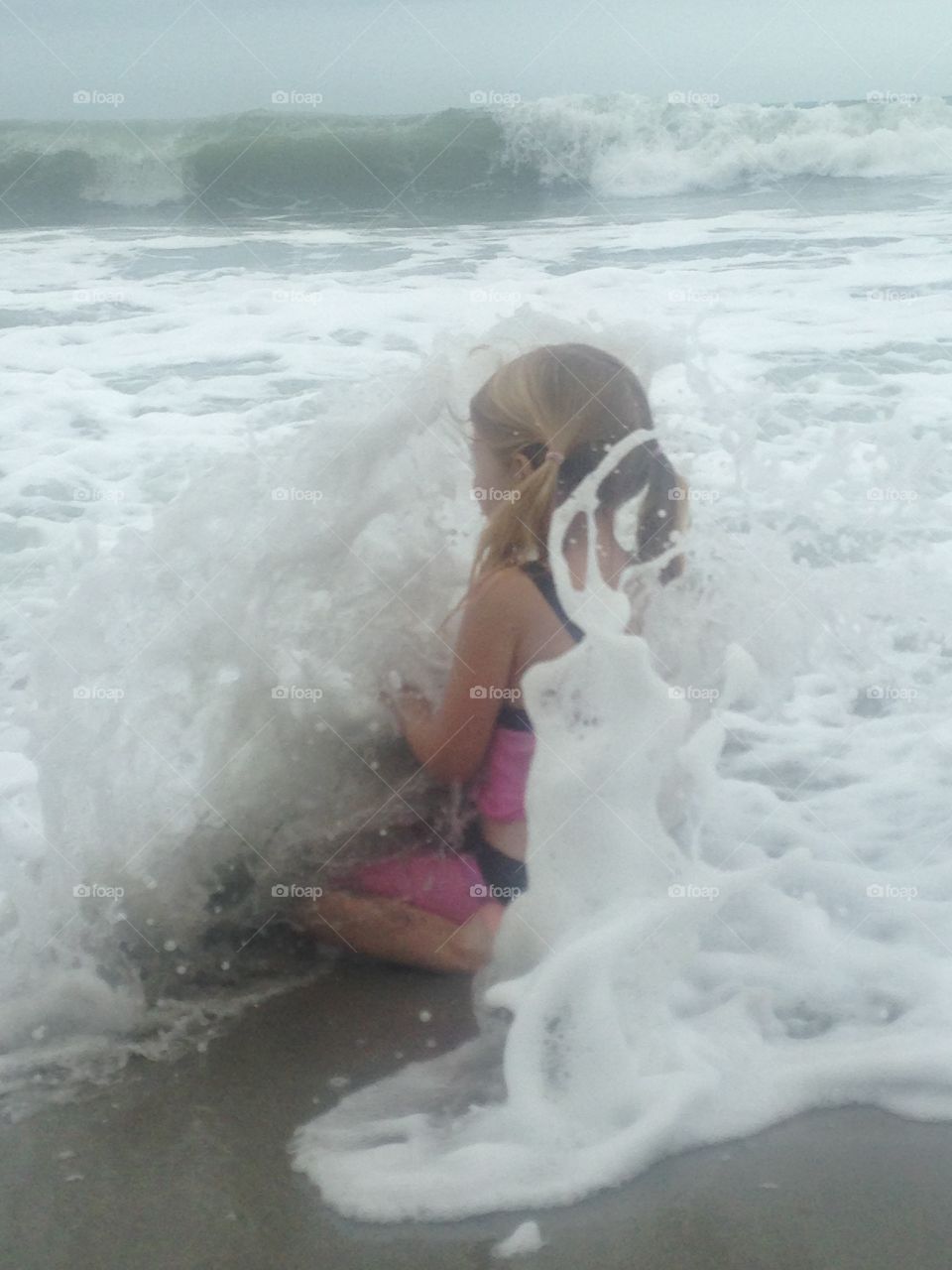 Little girl being splashed by waves 