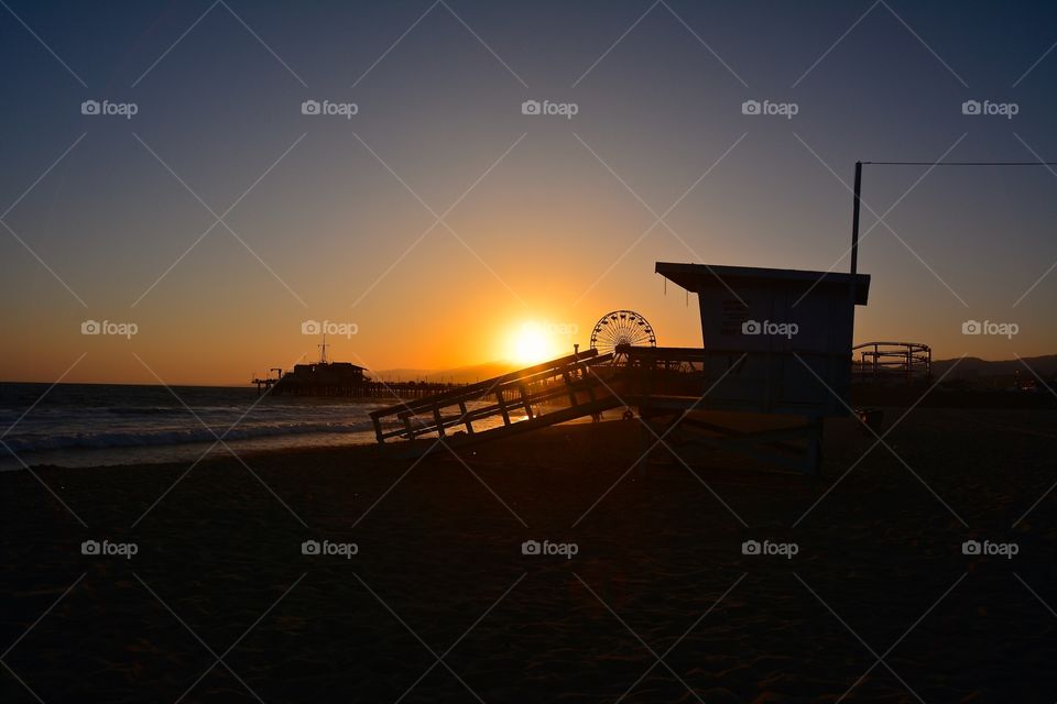 Silhouette of lifeguard tower at Santa Monica beach during sunset 