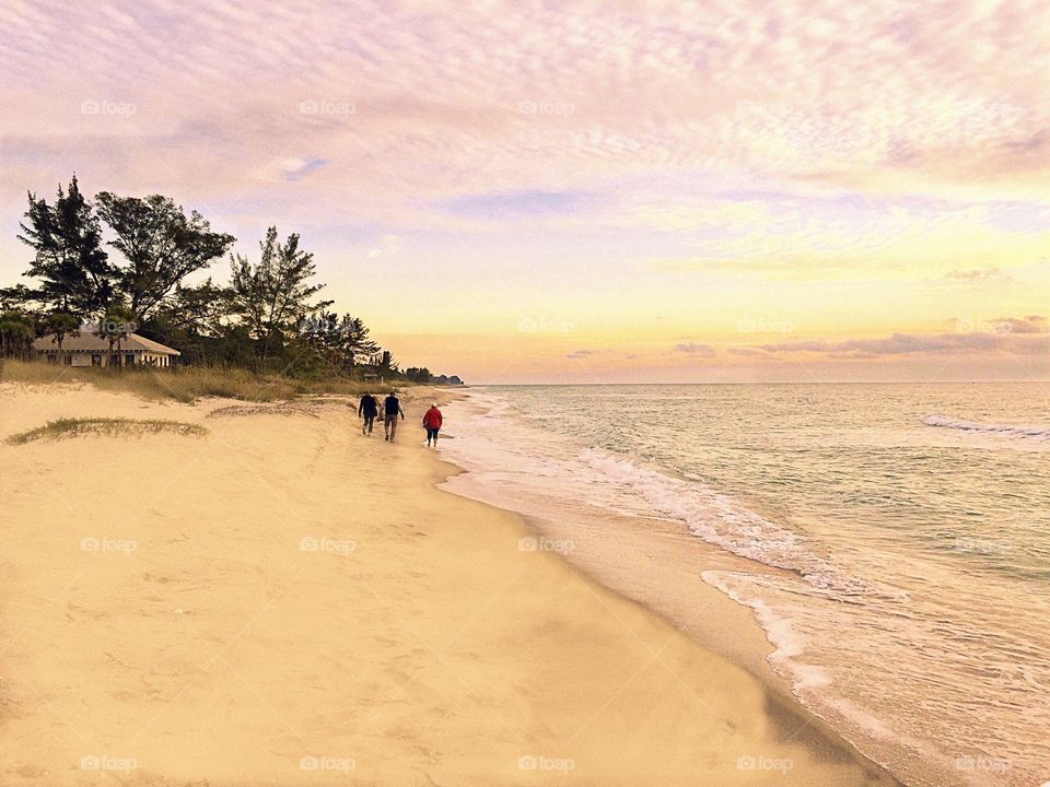 Beachcombers at a pastel sunset.