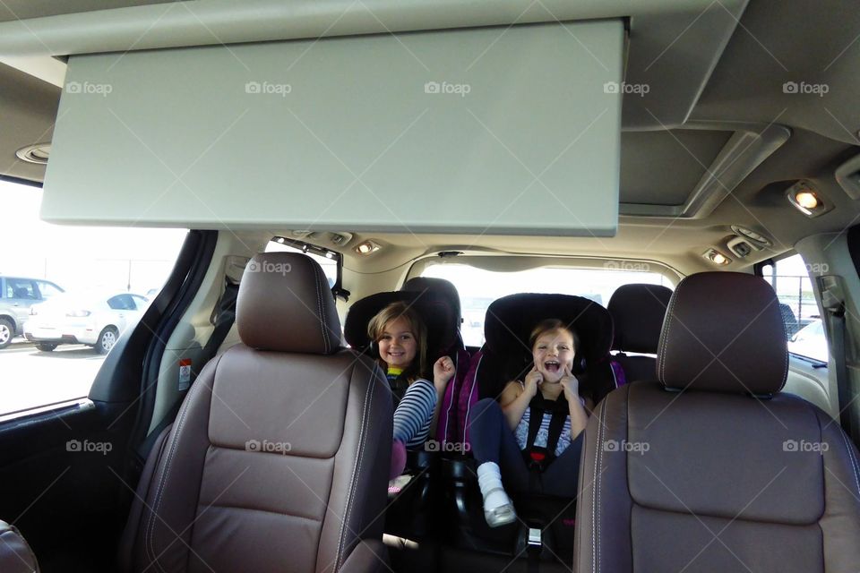 Kids in car seats in the 3rd row of a minivan