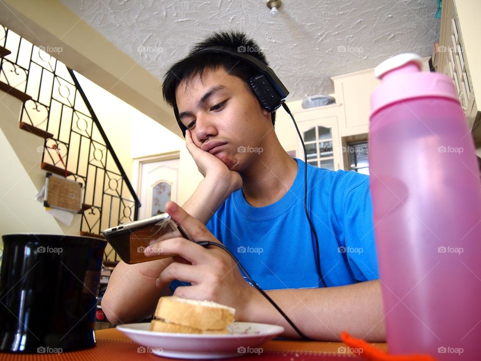 young teen eating snack while watching on a mobile device