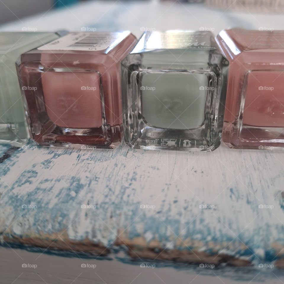 bottom of glass pin and green nailvarnish bottles lying down on shabby chic top. shiny