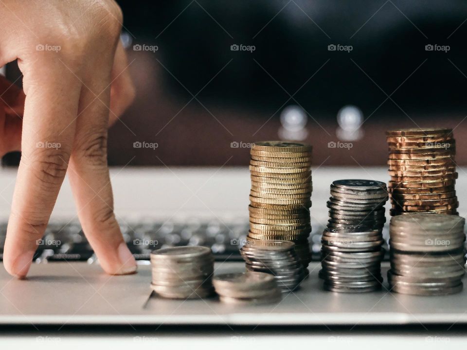 A finger walking towards the stacked coins