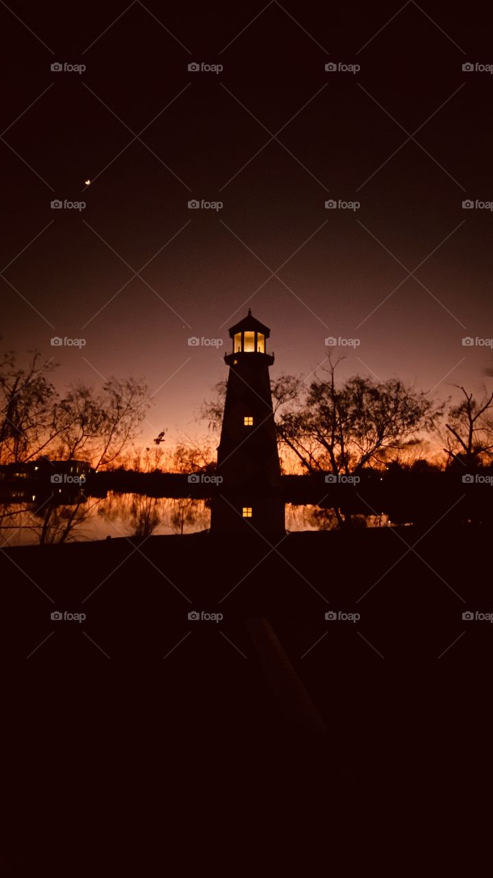 Lighthouse lit up beautiful Sunset Twilight. Magnificent Colors to represent perfect sunset. 