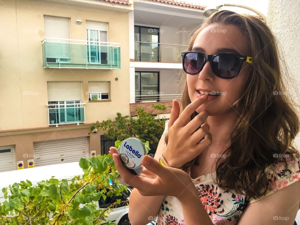 Young applying cream to her lips