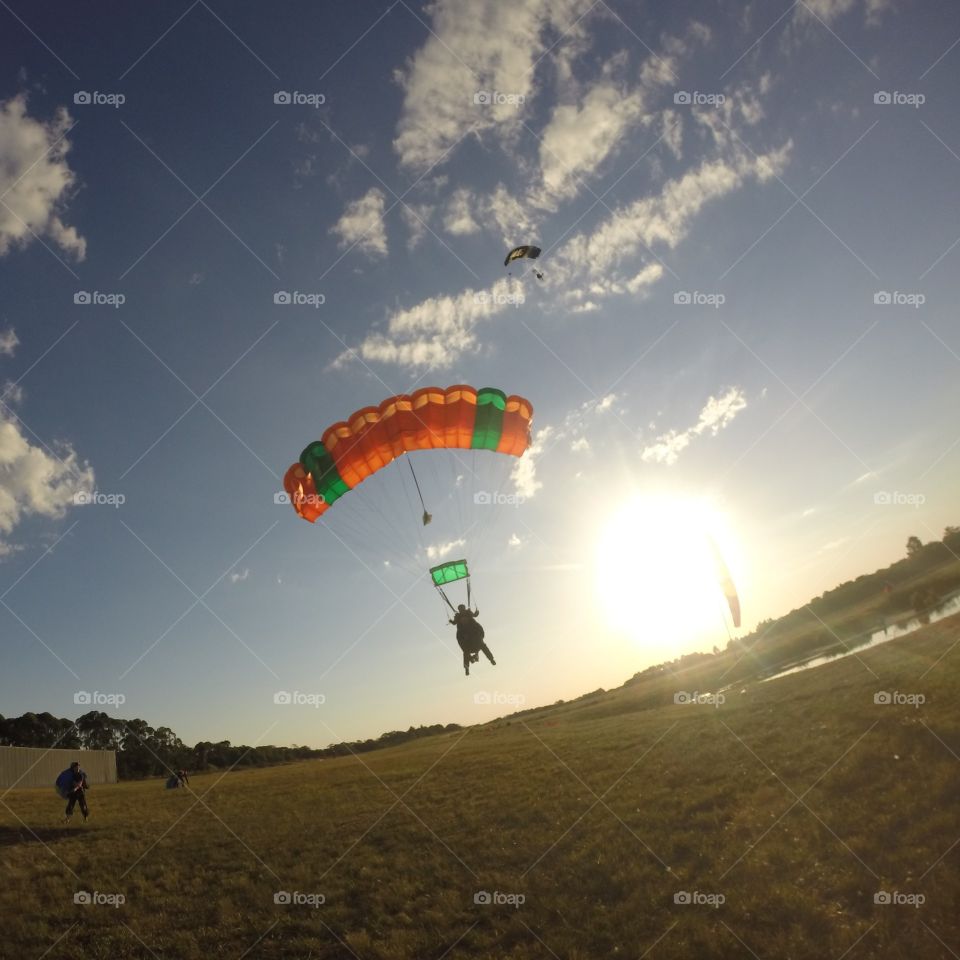 pôr do sol com paraquedas e nuvens