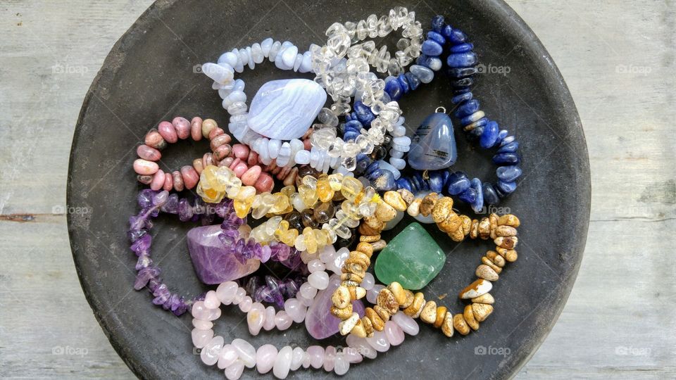 Gem stones in a black bowl on a grey wooden background