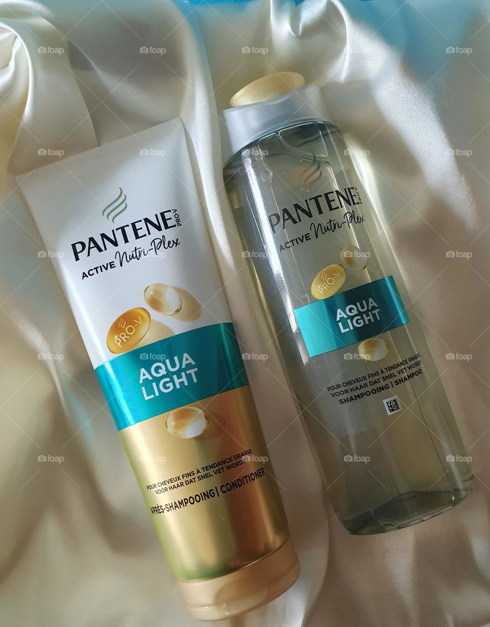 Product flatlay for Pantene Active Nutri-Plex Aqua Light shampoo and conditioner placed on ivory satin on which reflect bluish shadows