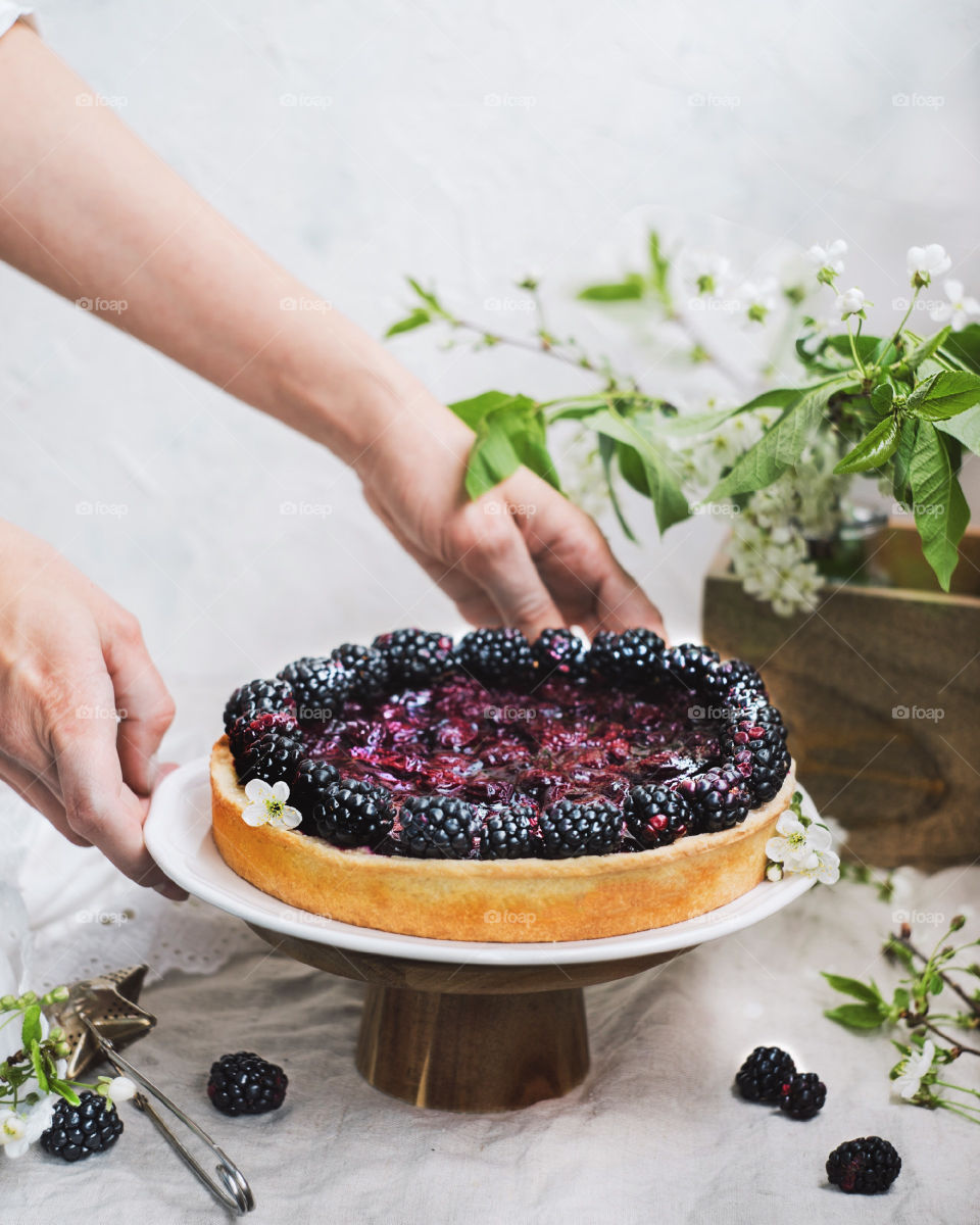 Girl's hands holding pie with cherries and blackberries.