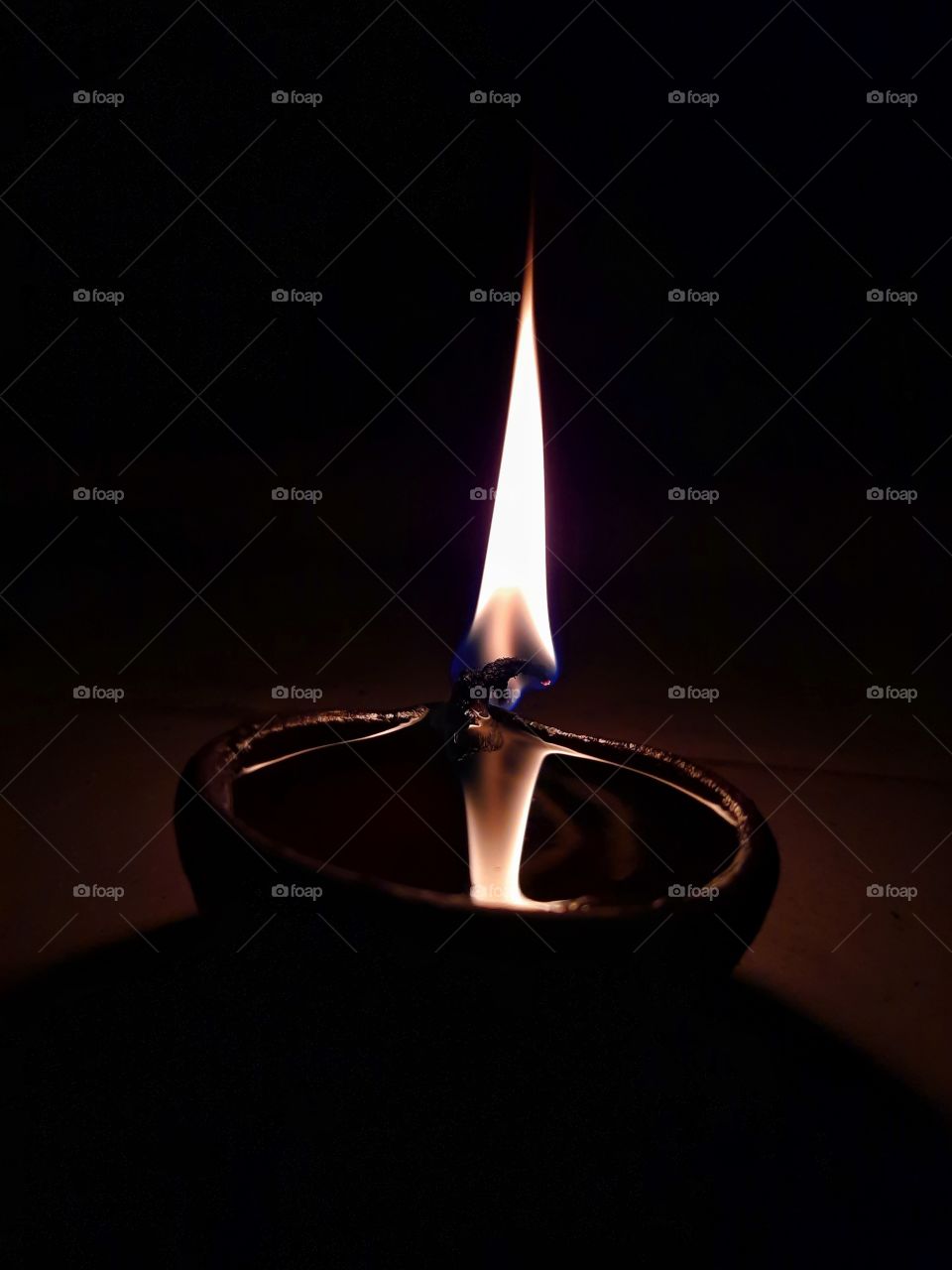 Burning bright and making the darkness go away. Clay oil lamp lighting the place amidst the darkness around.
