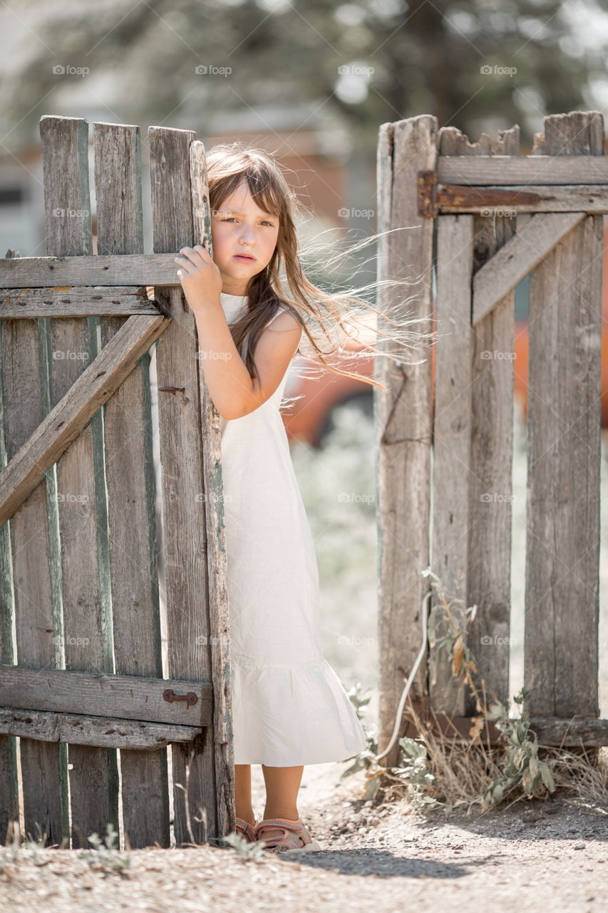 Girl portrait near old wooden fence at cloudy summer day