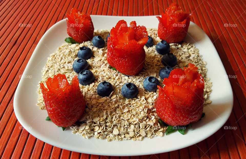 Quaker white oats decorated with blueberries and strawberries carved into roses.