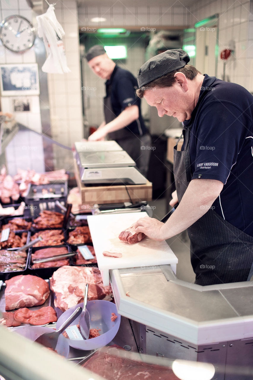 Butcher slicing up meat before selling it