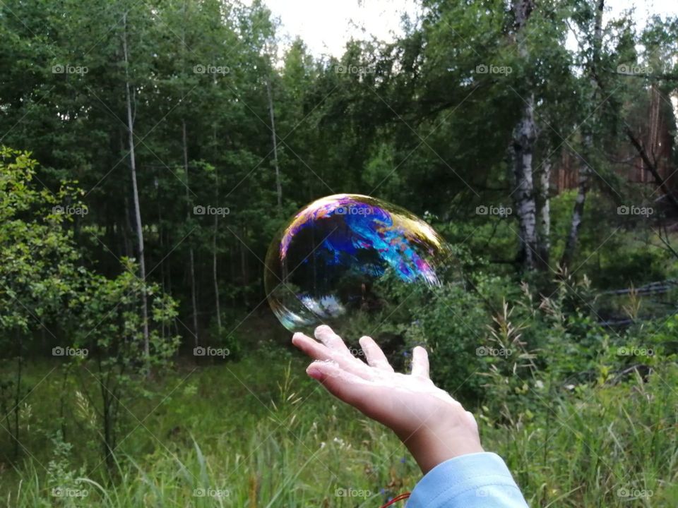 Soap bubble on hand in the forest in nature