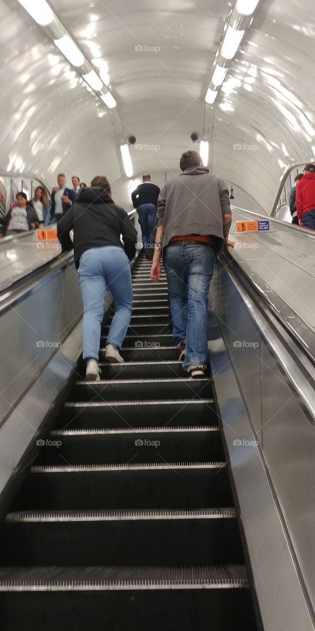 people walking up escalator in tube station london