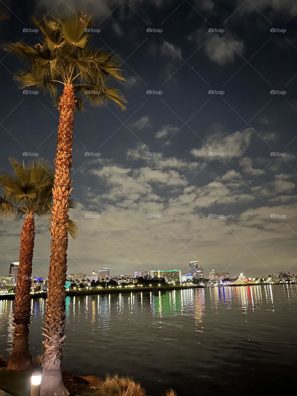 Looking across the water at the colorful twinkling lights of a seaside city during the magical twilight hour.