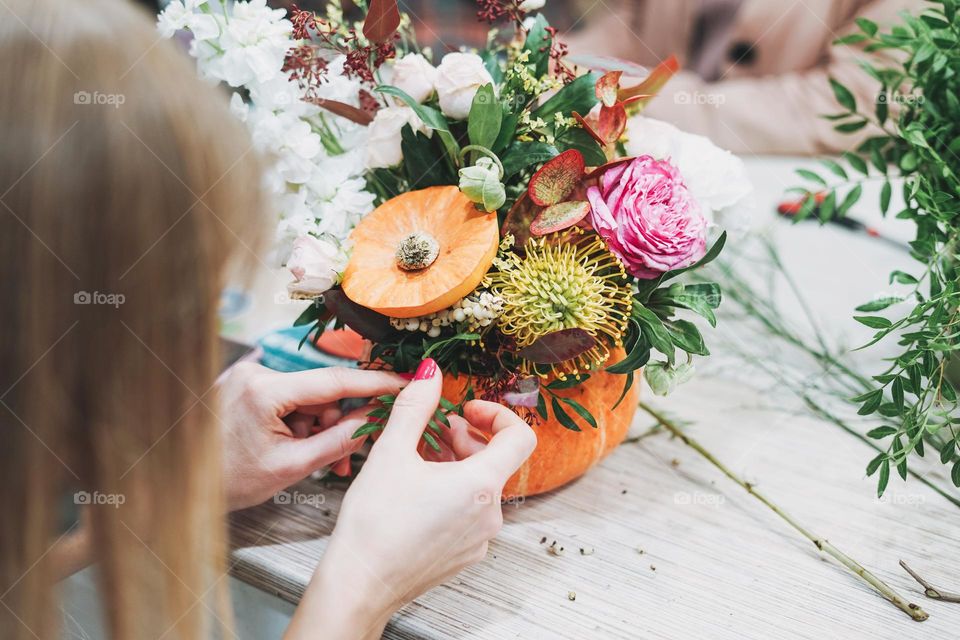 DIY autumn flower arrangement bouquet in pumpkin, florist at work, floristry studio