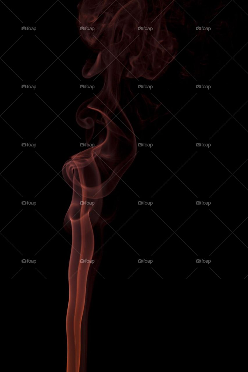 Orange abstract smoke swirling on black background