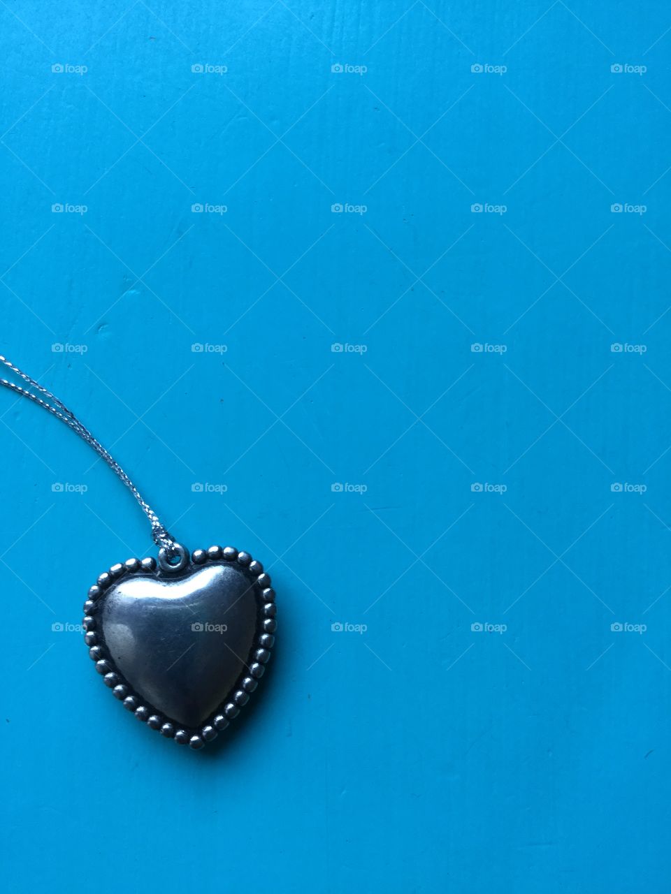 Blue background with silver heart. 