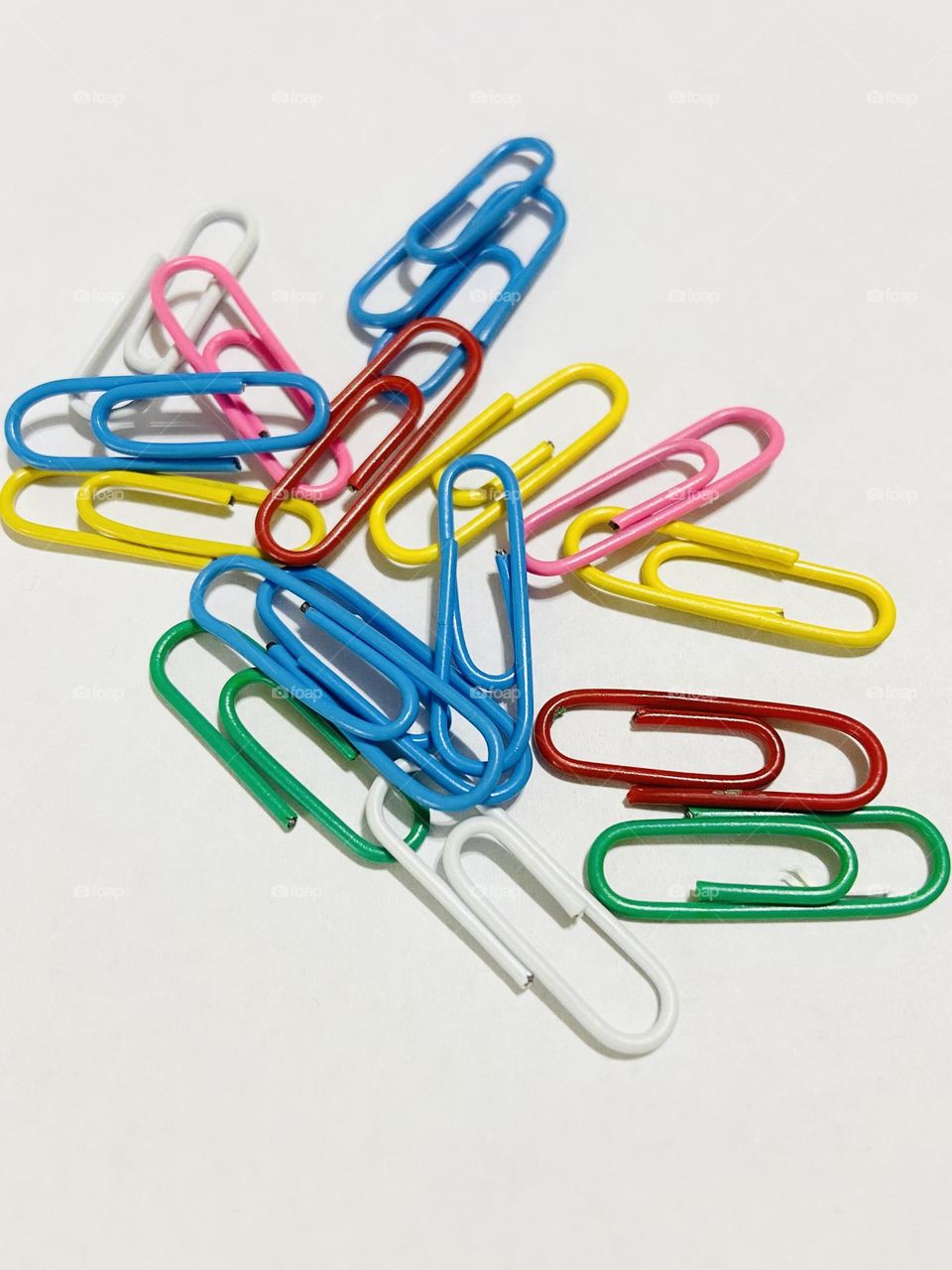 Bright colorful paper clips against a white background.