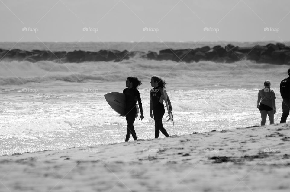 Two people walking with surf board near beach