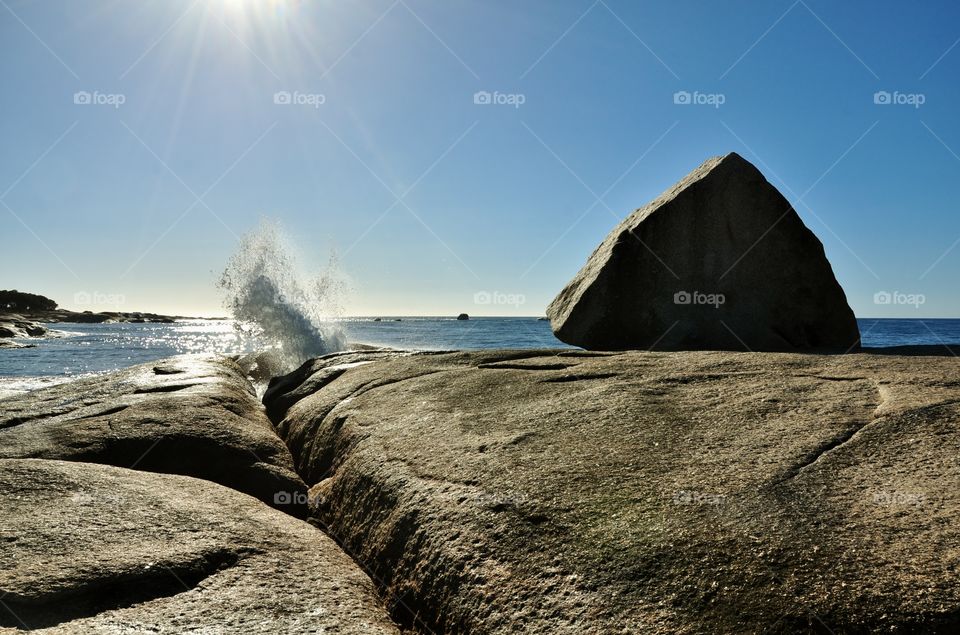Sun shining on ocean and rock blowhole 