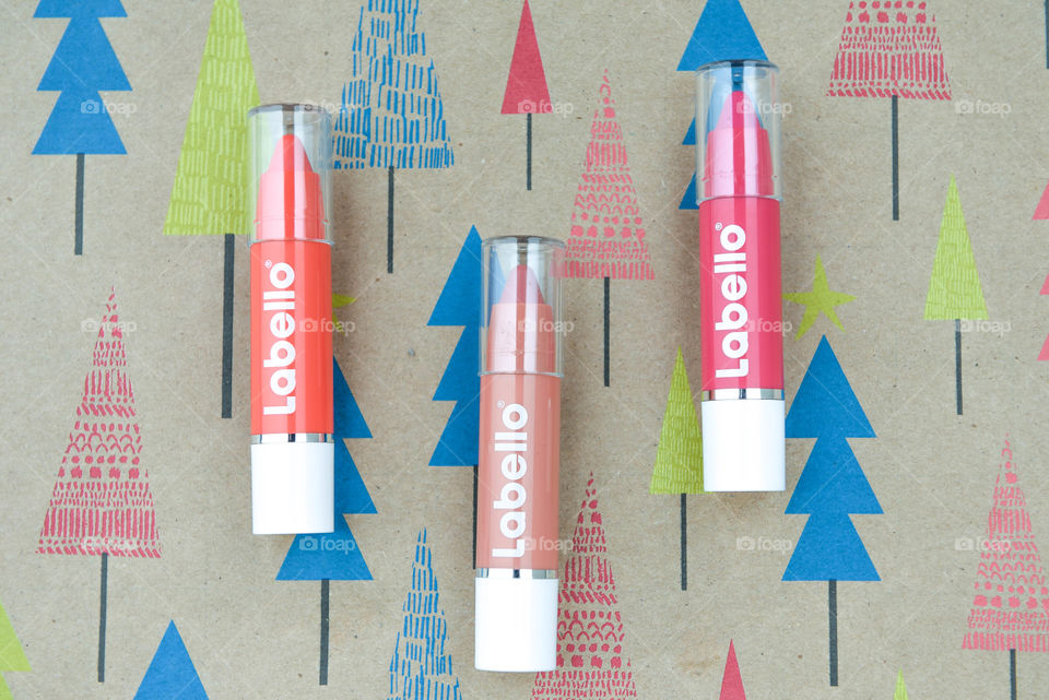 Row of Labello lip crayons on colorful holiday wrapping paper