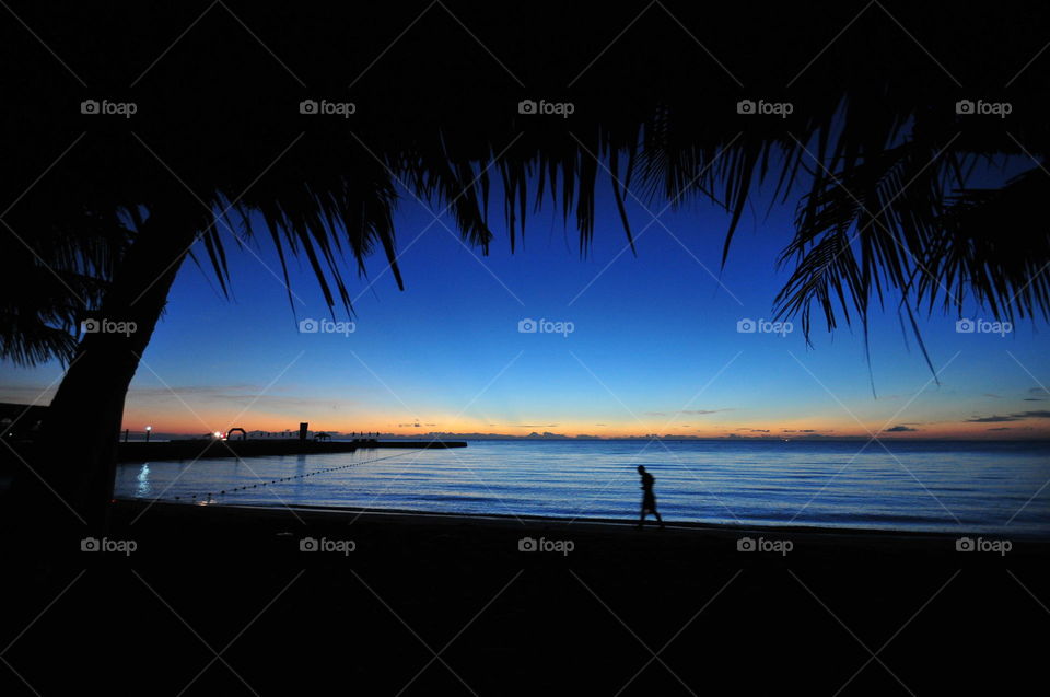 a man walks along a beach line while waitinf for the sunrise