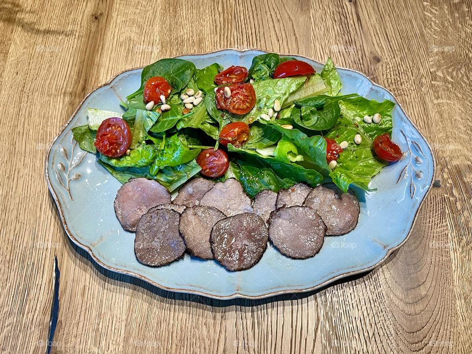 Blue plate with fresh salad, tomatoes, beef 