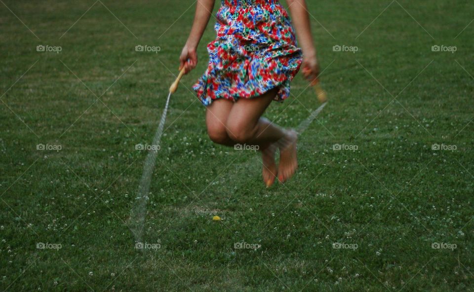 Woman with colorful dress jumping on rope at the park